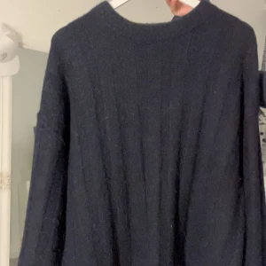 Mörkblå stickad tröja - Säljer en supermysig mörkblå stickad tröja som är perfekt för kyliga dagar. Den har en avslappnad passform och långa ärmar, Tröjan är i bra skick och passar perfekt till jeans eller leggings för en cas