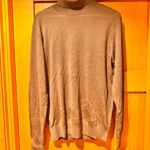 Brun polotröja från Jerem Black Collection - Säljer en snygg brun Turtle Neck  från Jerem Black Collection. Den är gjord av kashmir vilket gör den perfekt för kyliga dagar. Tröjan har en klassisk design med långa ärmar och en bekväm passform. Perfekt för både vardag och lite finare tillfäll