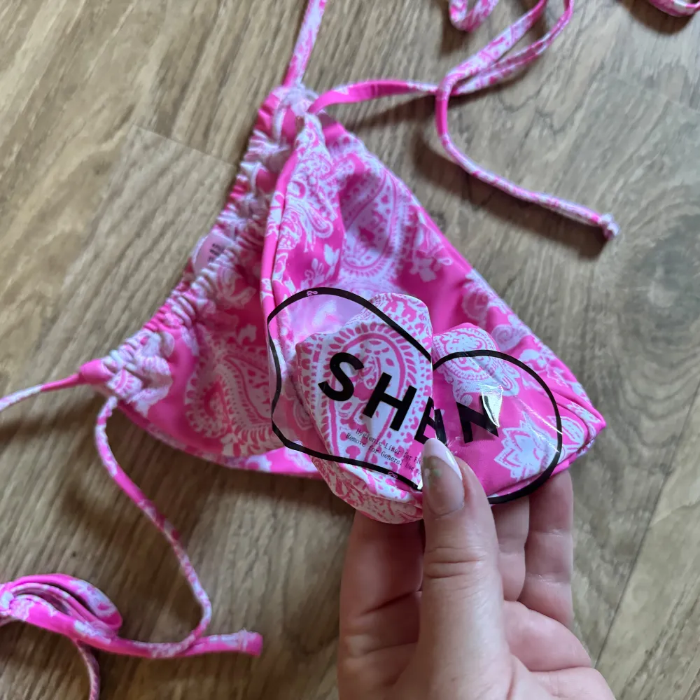 Säljer en superfin rosa bikiniunderdel från Shein. Den har ett snyggt paisleymönster i vitt och knytband på sidorna för perfekt passform. Perfekt för sommarens alla badäventyr! 🌸 Aldrig använda! . Övrigt.