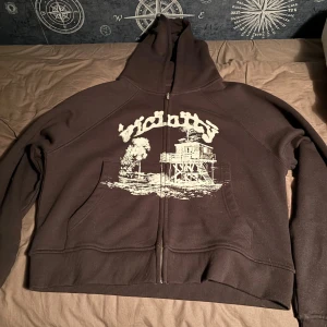 Brun hoodie från Vicinity - Säljer en svart hoodie från Vicinity i storlek medium. Den har en vit tryckdesign på framsidan och en dragkedja. Perfekt för höst och vinter, och den är i nyskick med taggen kvar. Superbekväm och stilren!