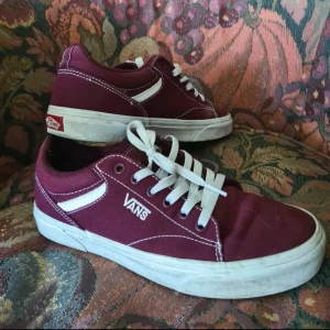 Vinröda Vans sneakers - Säljer ett par vinröda Vans sneakers storlek 40 i nästan nytt skick. Köpta för ett par år sedan men endast använt dem ett fåtal gånger. Sidan av sulan är något smutsiga men jag kan självklart försöka få rent dem så gott det går innan jag skickar 😊 