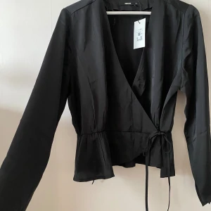 Satin blus - Svart omlott satin blus från bikbok. Helt oanvänd med prislapp kvar.