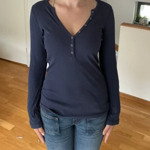 Mörkblå ribbad topp från Splendid - Säljer en mörkblå ribbad topp från Splendid i storlek S. Toppen har en v-ringning med knappar och långa ärmar. Perfekt för en casual look eller att klä upp med accessoarer. Toppen är i bra skick och väldigt bekväm att ha på sig.