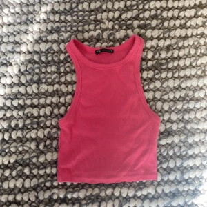 Rosa ribbad linnetopp från Zara - Säljer en superfin rosa ribbad linnetopp från Zara. Den är ärmlös och croppad, perfekt för sommardagar eller som ett lager under en jacka. Toppen är i storlek S och har en skön passform.