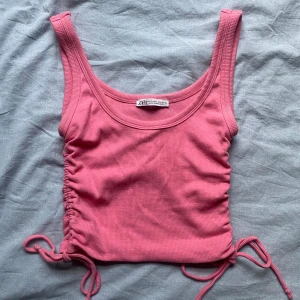 Rosa ribbad linnetopp från Zara - Säljer en superfin rosa ribbad linnetopp från Zara. Den har en tight passform och är ärmlös med snygga rynkade detaljer på sidorna som kan justeras med knytband! 🌸Nypris 200