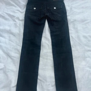 Svarta jeans från True Religion - Säljer ett par svarta lågmidjade jeans från True Religion i storlek 26. De är i bra skick men passade inte mig.