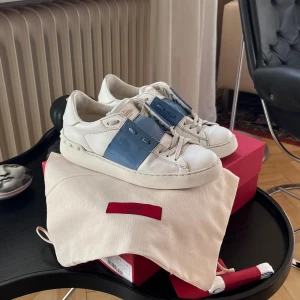 Valentino rockstud sneakers - Valentino rockstud sneakers i en glansig blå färg. Använt skick, inga skador förutom något repade framtill. Allt på bilden medföljer, dvs lådan, nya skosnören och skopåse. Köptes helt nya på Corner i Palma. 