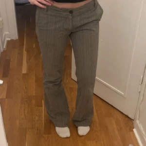 Randiga byxor - Säljer ett par snygga randiga byxor. De är gråa med vita och blåa ränder och har en låg midja. Byxorna är perfekta för hösten. De är i bra skick och passar både till vardags och fest.