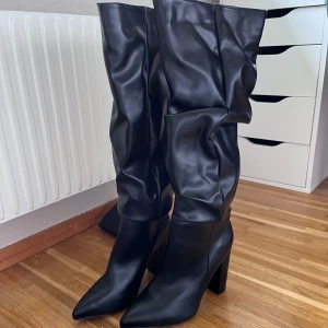 Svarta stövlar med klack - Säljer ett par snygga svarta stövlar i skinn med hög klack och spetsig tå. Perfekta för höst och vinter, dessa stövlar har en stilren design som passar både till vardags och fest. De är i nyskick och redo att användas! (har aldrig använt) 