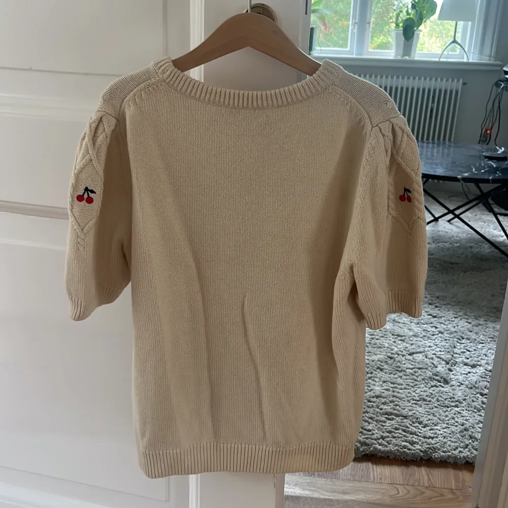 Tröjan är i färgen beige och har fina körsbär som detaljer. Den är från början köpt på Lucca. Tröjan är i mycket bra skick. Köparen står också för frakt.. Stickat.