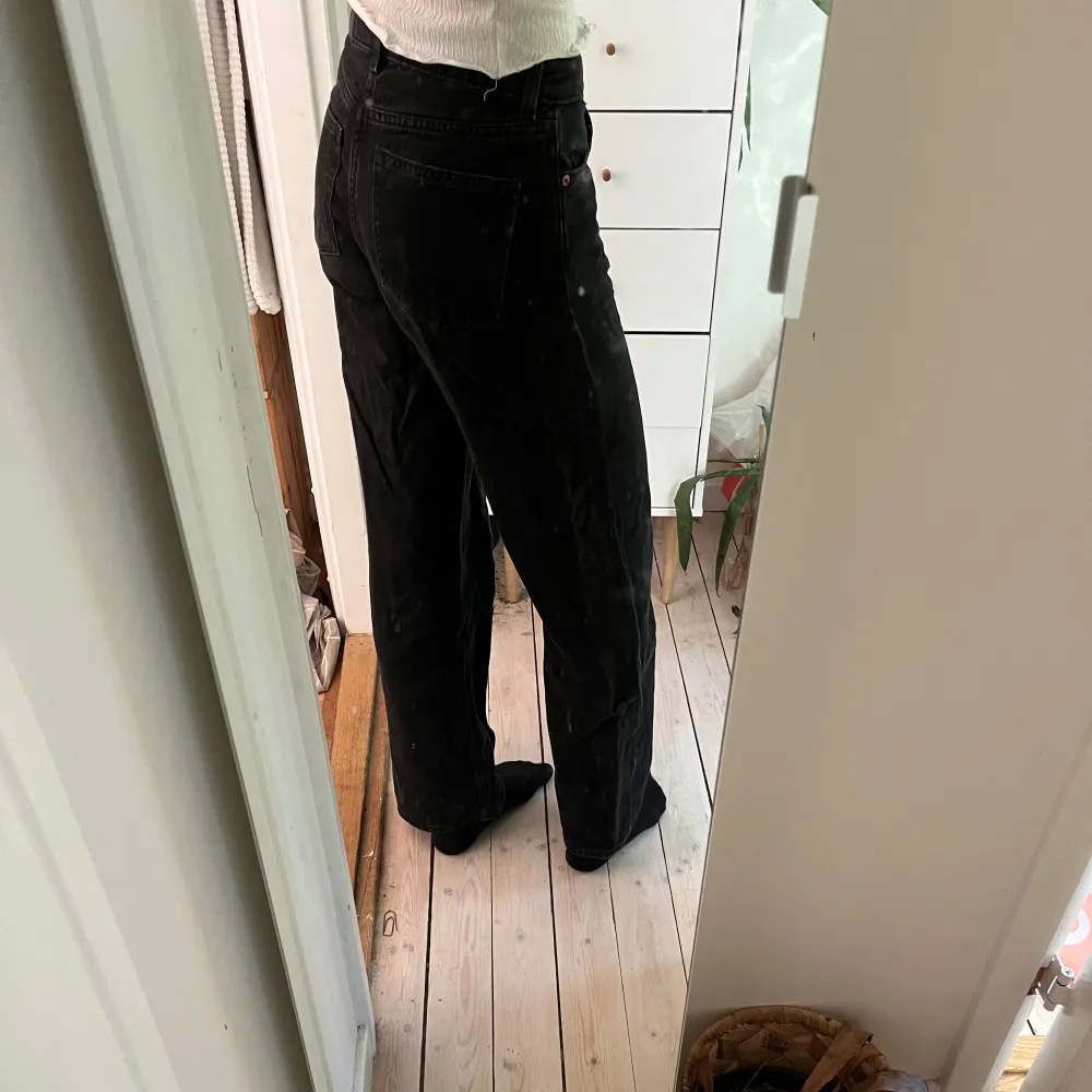 Svarta jeans med vida ben. En fläck längst ner på benet som inte går bort i tvätten. Midjemått: 36 cm rakt över. Innerbenslängd: 77 cm. Jeans & Byxor.