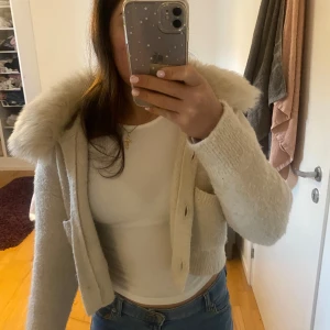 Beige stickad jacka med pälskrage - Har knappt använd den, är i nyskick. Man kan även ta bort pälsen ifall man vill, priset kan alltid diskuteras.