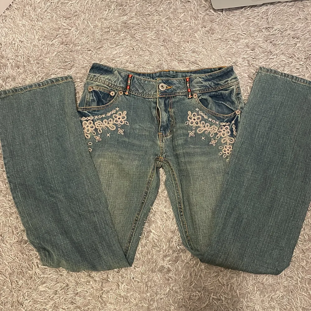 Vintage bootcut/straight midwaist jeans med blomdetaljer både fram och bak Innerbenslängd: 79 cm Midejemått: 38.5 cm tvärs över Priset kan diskuteras  Skriv för fler bilder. Jeans & Byxor.