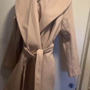 Beige kappa  - Beige kappa från Vila  Sjalkrage Försluts med skärp  Storlek 42 Nypris 599 kr  Använd 1 gång 