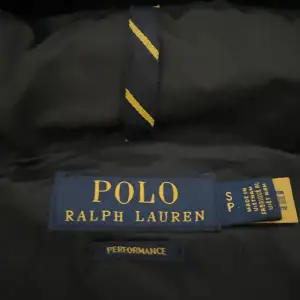 Säljer en svart pufferjacka från Polo Ralph Lauren. Jackan är perfekt för kalla dagar med sin quiltade design och varma fyllning. Den har en dragkedja framtill och en praktisk huva för extra skydd mot väder och vind. Jackan är i storlek M och passa p