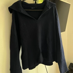Mörkblå stickad tröja från Gina Tricot - Säljer en mysig mörkblå stickad tröja från Gina Tricot. Tröjan har en v-ringad krage och långa ärmar med ribbade muddar. Superbekväm och stilren!