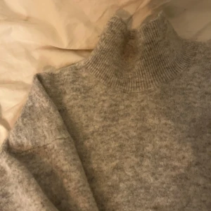 Grå stickad polotröja - Mysig grå stickad polotröja i mycket bra skick. Perfekt för kalla höst- och vinterdagar. Den har långa ärmar och en ribbad polokrage som håller dig varm och bekväm. Passar både till vardags och lite finare tillfällen.