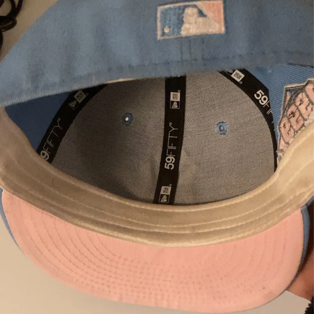 Säljer en snygg pastel blå New Era keps fitted med vit broderad logga framtill.                Kepsen har en rosa underskärm och ett 1999 All-Star patch på sidan. Storleken är 7 /14, 57,7cm. Priset kan förhandlas . Accessoarer.