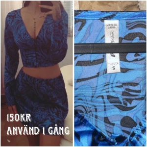 Blå och svart mönstrad klänning  - Säljer en blå och svart mönstrad sett, använd endast en gång. Klänningen har en djup v-ringning och långa ärmar. Perfekt för en utekväll eller fest! 💙