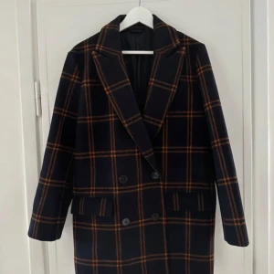 Ullkavaj/kappa från & Other Stories  - Rutig kappa i ull med dubbelknäppning i storlek 34. Modellen är oversized och passar även mig i storlek 38 för en mer dressad look. 50% ull 50% polyester.