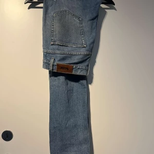 Blå jeans från Acne - Säljer ett par klassiska blå jeans från Acne i mycket bra skick. De har en rak passform och är perfekta för både vardag och fest. Jeansen har en snygg, enkel design med en bakficka och en läderpatch med Acne-loggan. Perfekt för dig som vill ha en stilren look!