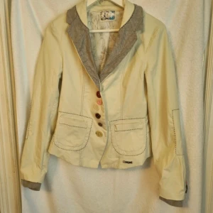 Desigusl beige/krämvit jacka - Krämvit/beige jacka från Desigual. Mycket fint begagnat skick. Storlek 40 men liten i storleken mer som en 38 (Färgen stämmer överens med bild 4 och 5.)