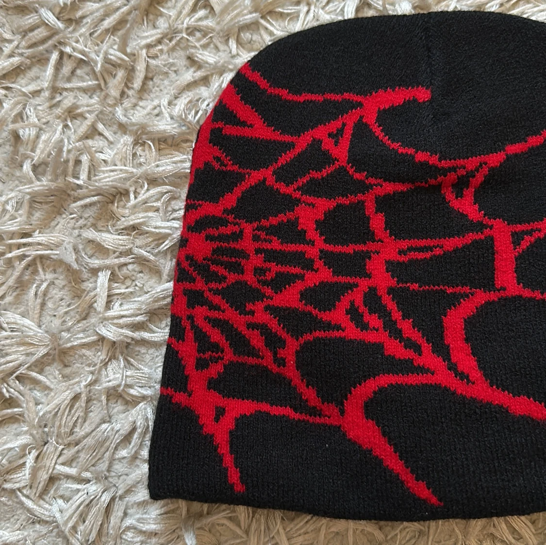 Svart mössa med rött spindelnätsmönster - 92
