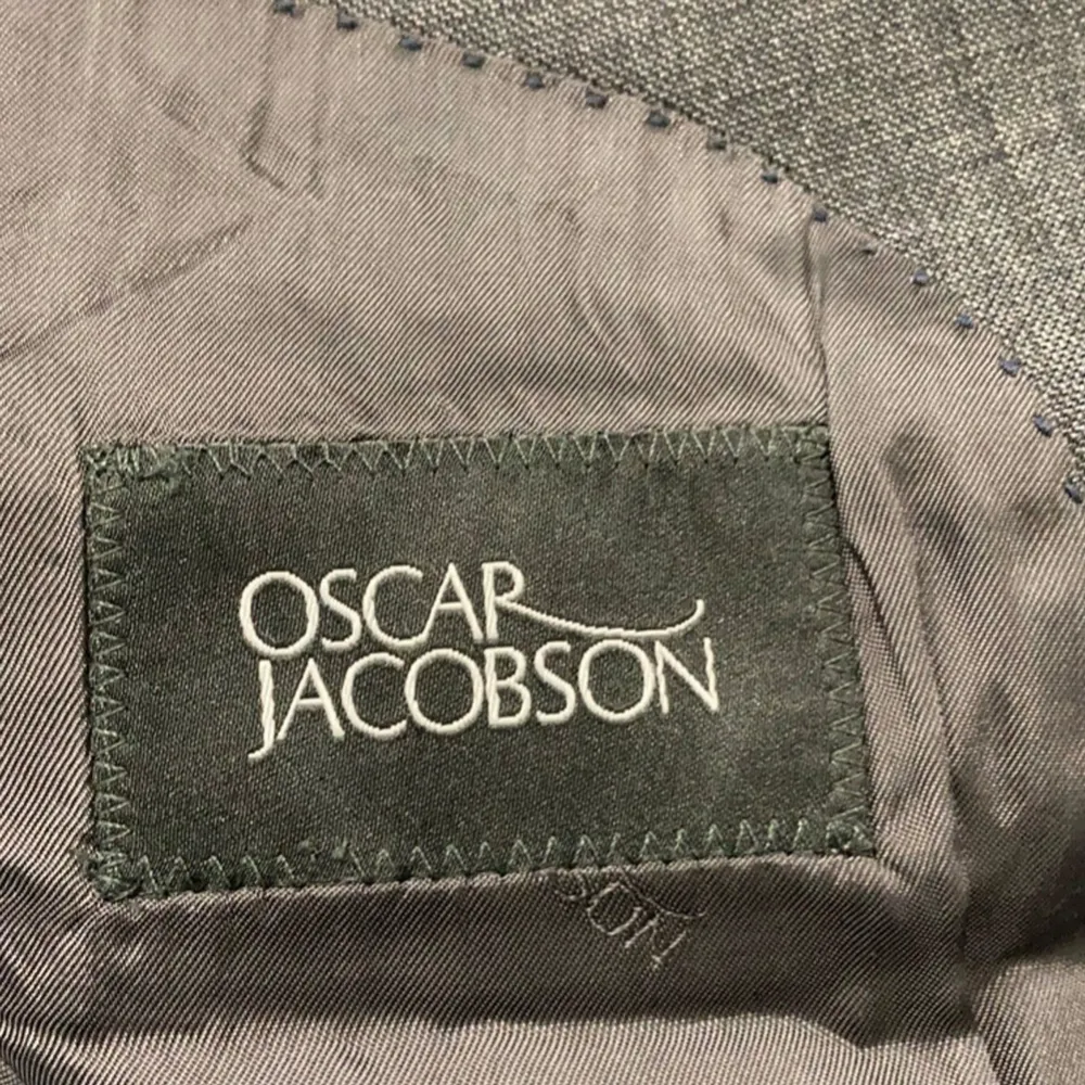 Säljer en stilren svart kavaj från Oscar Jacobson i herrstorlek. Kavajen har en klassisk passform med två knappar framtill och är perfekt för både formella och semi-formella tillfällen. Materialet känns lyxigt och är av hög kvalitet. Perfekt för höst och vår!. Puvut & Bleiserit.