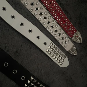 Snygga nitarbälten i olika färger - Säljer coola bälten med nitar i rött, vitt och svart. Perfekta för att ge din outfit en edgy touch. Bältena har olika mönster av nitar och stenar, vilket gör dem unika och stiliga. Passar perfekt för både fest och vardag. Gör din stil mer rockig med dessa bälten! Obs! Röda bälten finns ej kvar en bälte är 79 alla blir 180