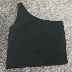 Svart oneshoulder topp från Gina Tricot - Snygg svart oneshoulder topp från Gina Tricot i storlek XL. Perfekt för en utekväll eller fest! Toppen är ribbad och har en stilren design som passar till det mesta. Ett måste i garderoben för den som gillar att sticka ut lite./ passar L också 🤩 