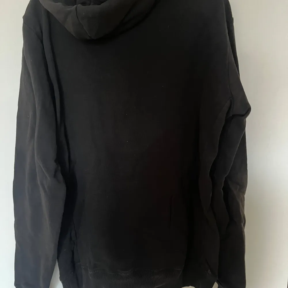 Säljer en svart hoodie från Les Deux i storlek M. Den har en röd text på framsidan och en klassisk känguruficka. Perfekt för en avslappnad stil och passar bra till både höst och vinter. Huvan har justerbara snören för extra komfort.. Tröjor & Koftor.