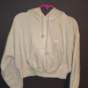 Beige hoodie från Levi's - Säljer en supermjuk och bekväm beige hoodie från Levi's. Den har en klassisk känguruficka och justerbar dragsko i huvan. Perfekt för en avslappnad stil och passar till alla årstider. Den är i mycket bra skick och redo för nya äventyr!