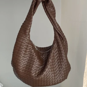 Brun flätad axelväska - Snygg brun axelväska i flätat mönster med dragkedja. Köpt förra veckan så i väldigt fint skick. Helt slutsåld online. Från Gina tricot. Köpt för 499 kr. 