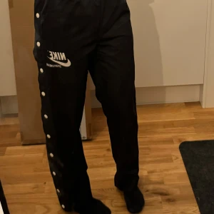 Nike trackpants - Svarta trackspants från Nike. Äkta. Inköpta för några år sedan.  I välbevarat skick, nyskick skulle jag bedöma.  Går att knäppa upp hela vägen på båda sidor.  Strl XS men jag är en S och de sitter som en smäck.