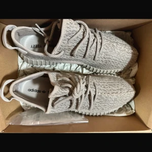 Adidas Yeezy Boost 350 i beige - Säljer ett par Adidas Yeezy Boost 350 i en stilren beige färg. Skorna har en stickad ovandel med snörning och den ikoniska ribbade sulan. Perfekta för en trendig look.