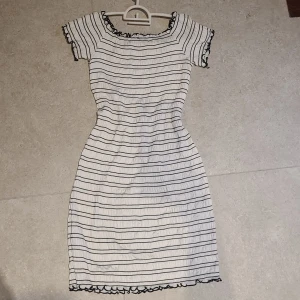 Randig klänning med volangdetaljer - Säljer en söt randig klänning i vitt och svart med volangdetaljer vid hals och ärmslut. Klänningen har en tight passform och är offshoulder. Väldigt mjukt och tunnt material perfekt för sommaren. Från Lindex tror jag i barnstorlek men passar som en S/M och kanske en L då den är väldigt stretchig.