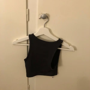 Svart croppad linnetopp från Monki - Säljer en stilren svart croppad linnetopp från Monki. Perfekt för en trendig look, med ärmlös design och rund halsringning. Passar utmärkt till både jeans och kjol. 🖤