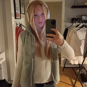 Grå fleeceväst från Peak Performance - Säljer en grå fleeceväst från Peak Performance med dragkedja framtill och två praktiska fickor. Perfekt för lager-på-lager under kyligare dagar. Västen har en hög krage för extra värme.