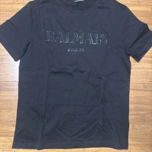 Svart t-shirt från Balmain - Snygg svart t-shirt från Balmain med tryck framtill. Perfekt för en stilren look.