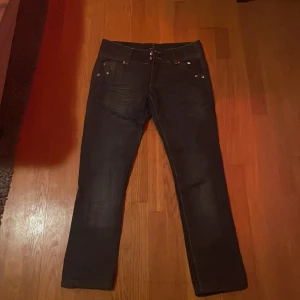 Svarta jeans från Ed Hardy - Snygga svarta jeans från Ed Hardy med broderad logga på baksidan. De har en klassisk femficksdesign och coola knappar med mönster. 