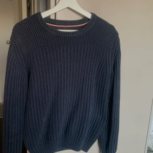Mörkblå stickad tröja - Säljer en stilren mörkblå stickad tröja med rund halsringning. Tröjan har långa ärmar och en ribbad struktur som ger en klassisk look. Perfekt för kyligare dagar. Storlek XS men som en S