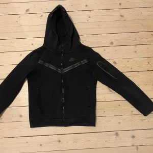 Nike tech fleece  - Säljer ett svart från Nike i mycket bra skick. Setet består av en långärmad hoodie med dragkedja och matchande byxor med snörning i midjan. Perfekt för träning eller chill dagar. Materialet känns mjukt och bekvämt.