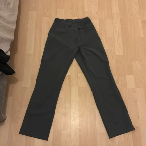 Grå kostymbyxor - Snygga grå kostymbyxor med en klassisk straight passform. Perfekta för en stilren look. Byxorna har en diskret dragkedja och knapp framtill.