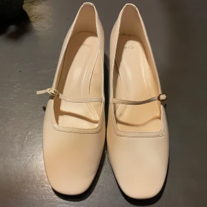 Beige ballerinaskor med låg klack - Eleganta beige ballerinaskor med en smal rem över foten och en liten klack. Perfekta för en stilren look.