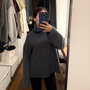 Grå stickad polotröja - Mysig grå stickad polotröja med långa ärmar och ribbade detaljer vid ärmslut och nederkant. Perfekt för kyliga dagar.