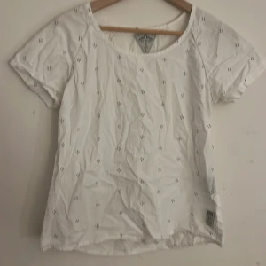 Vit t-shirt från Iconic Sport - Säljer en vit t-shirt från Iconic Sport med små svarta prickar. T-shirten har en rund halsringning och korta ärmar. Perfekt för en avslappnad stil.