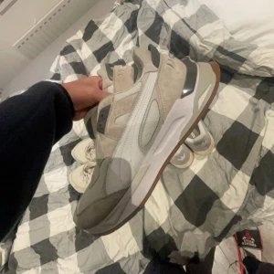 Puma RS-X - Snygga puma skor i beige och vitt med en robust sula i brunt. Skorna har en stilren design med detaljer i mocka och syntetmaterial. Perfekta för en avslappnad stil.