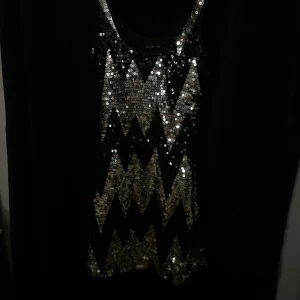  paljettklänning från Vila - Snygg svart klänning från Vila i storlek XS, täckt med glittriga paljetter i ett zigzag-mönster. Perfekt för en festlig kväll med sin iögonfallande design.