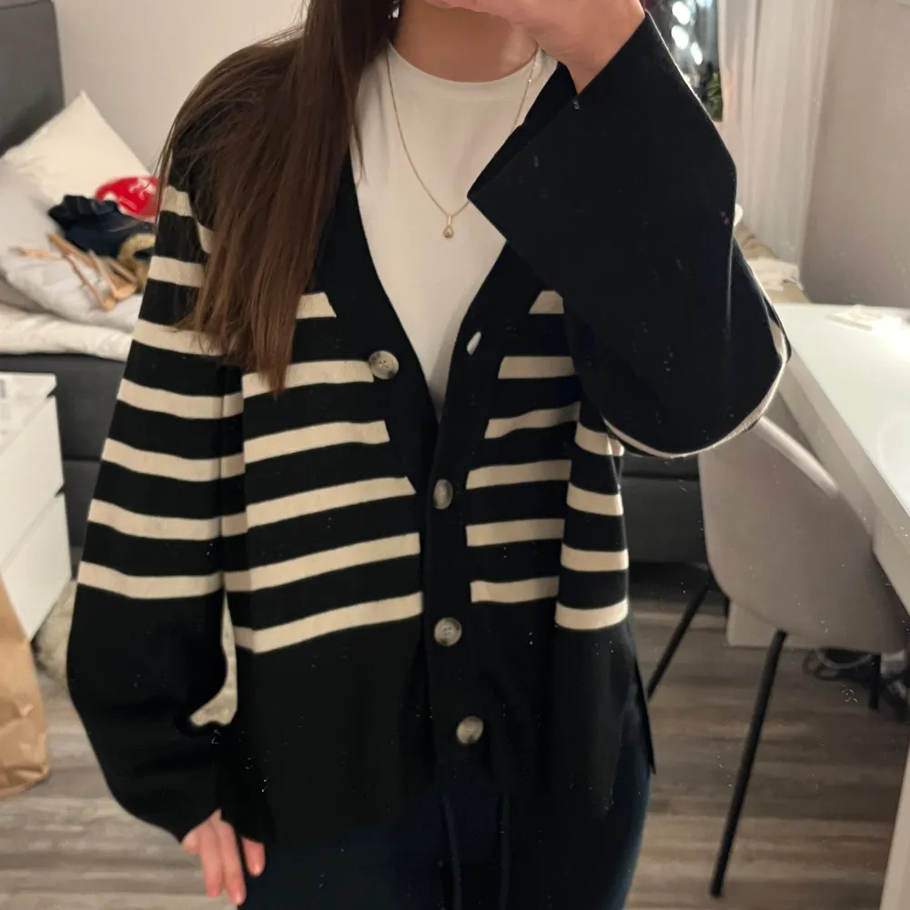 Säljer en snygg svart och vit randig kofta från Object. Koftan har stora knappar framtill och långa ärmar. Perfekt för en stilren look.. Neuletakit & Villapaidat.