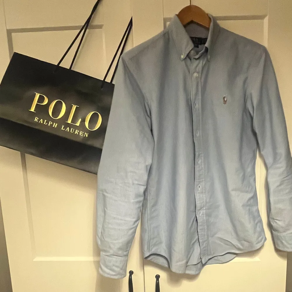 Snygg blå skjorta från Ralph Lauren i custom fit. Skjortan har långa ärmar och knappar framtill. Perfekt för en stilren look. Köpt i butik . Paidat.